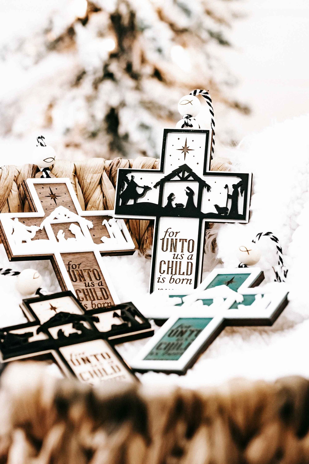 Assorted white, black, and teal nativity cross ornaments with verse text and star