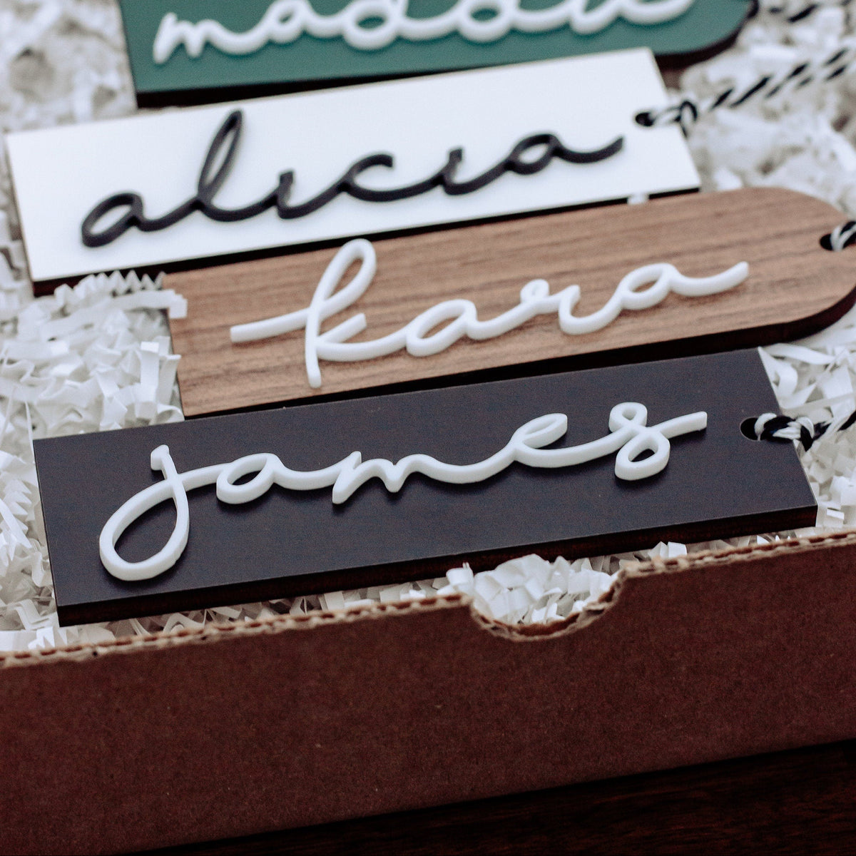 Personalized wooden name tags in white script on wood planks, multiple colors