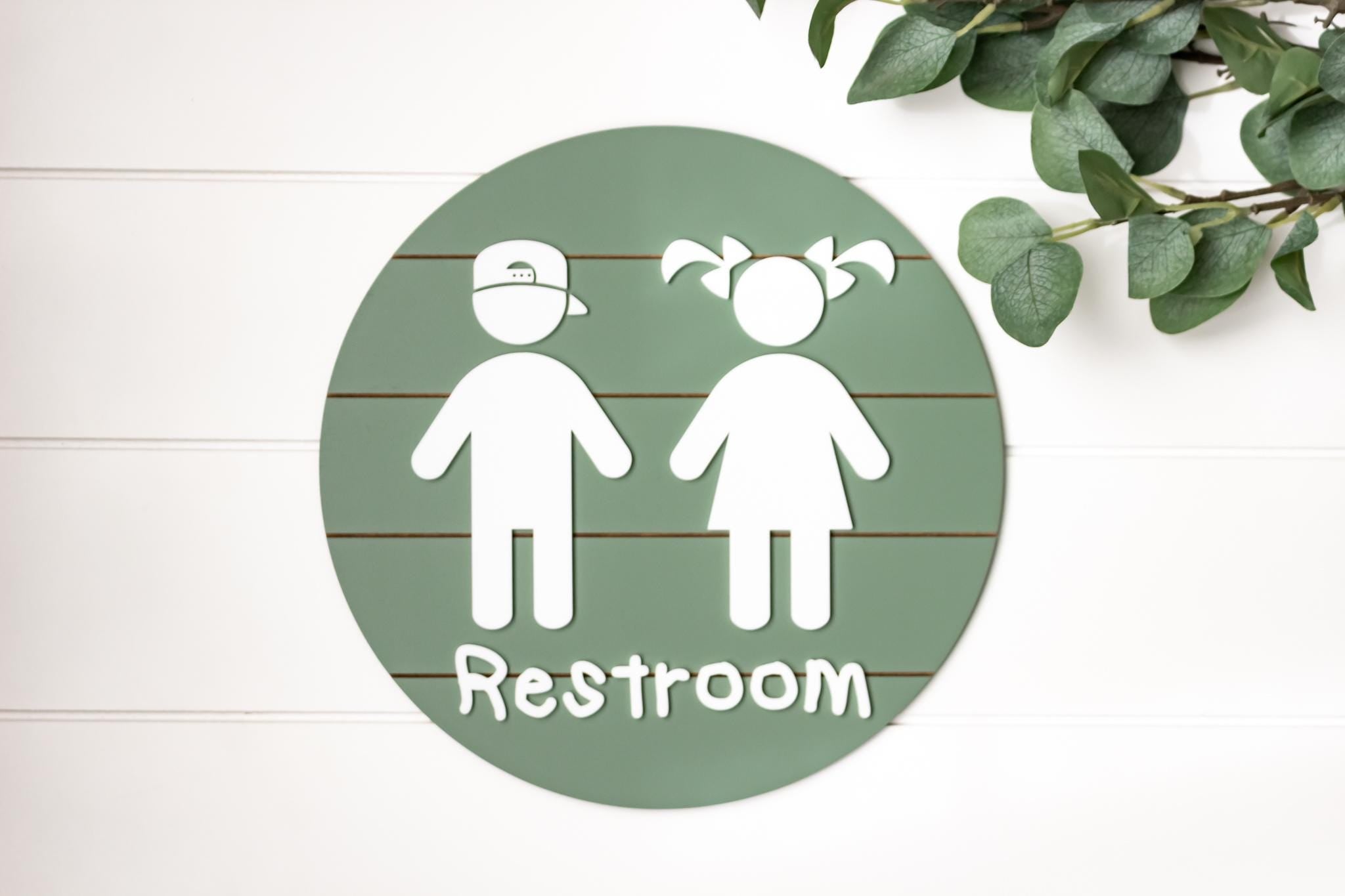 Round 3D toddler restroom sign, green with two white child figures and “Restroom”