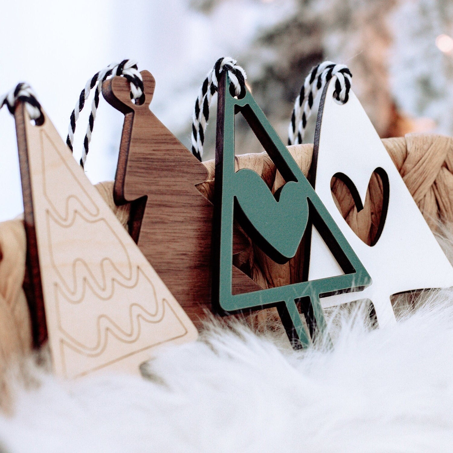 Wooden Christmas tree ornaments with striped string loops; green and brown pieces on snow