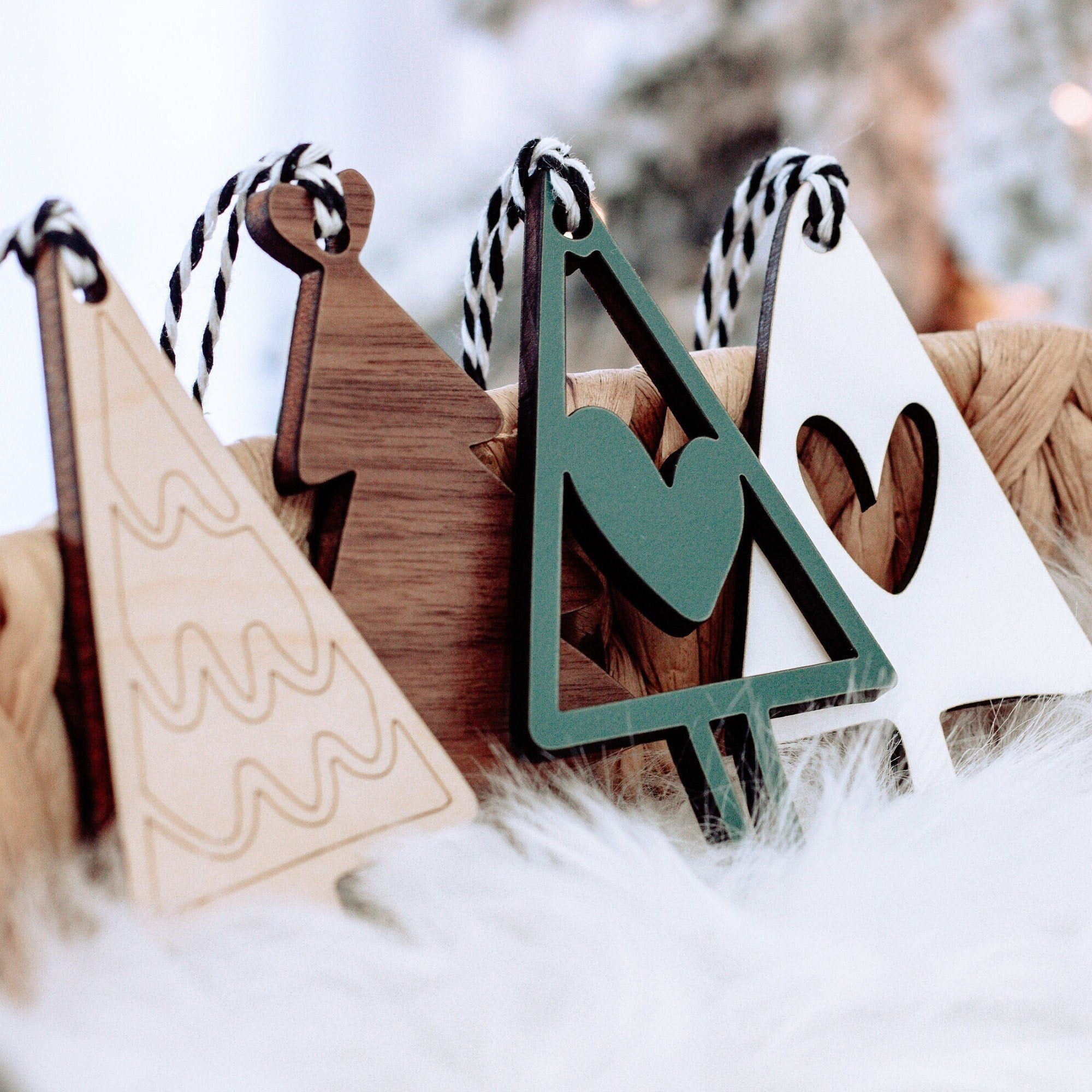 Wooden Christmas tree ornaments with striped string loops; green and brown pieces on snow