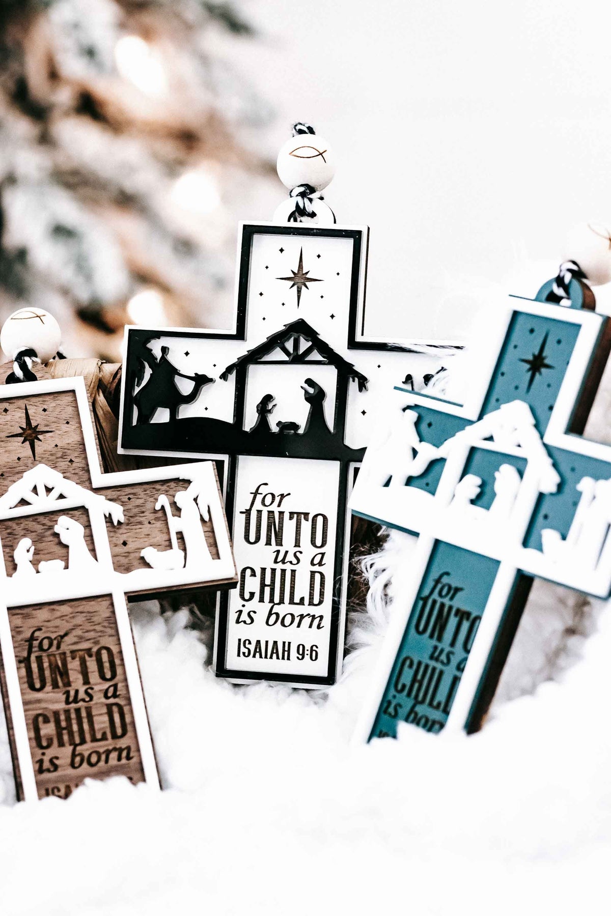 Assorted nativity cross ornaments in white, black, and teal/blue with star and silhouettes