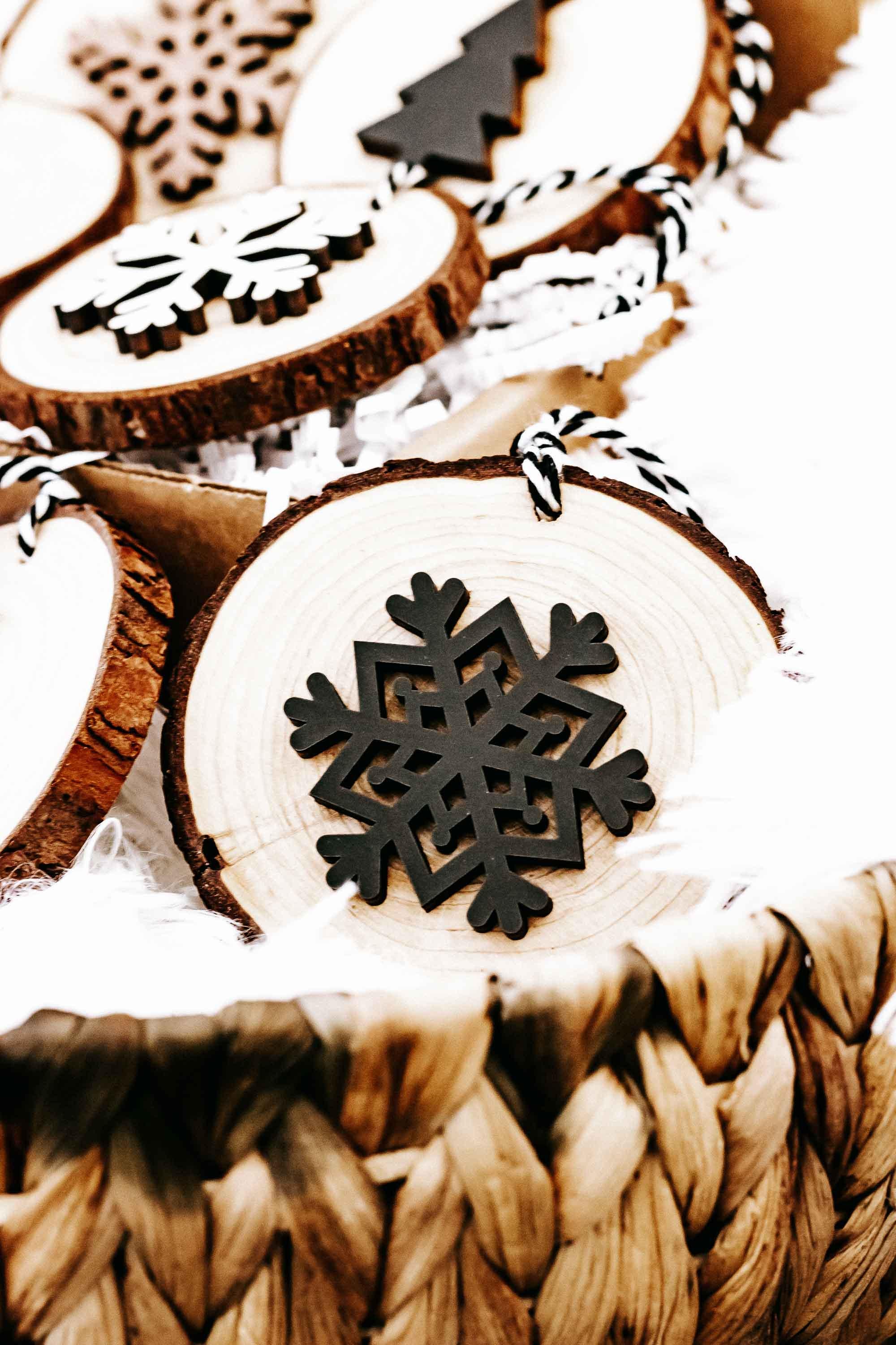 Wood slice ornament with large black snowflake cutout and string loop, part of set