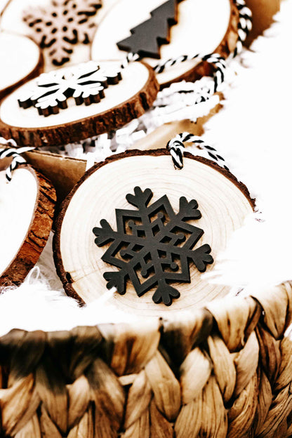 Wood slice ornament with large black snowflake cutout and string loop, part of set