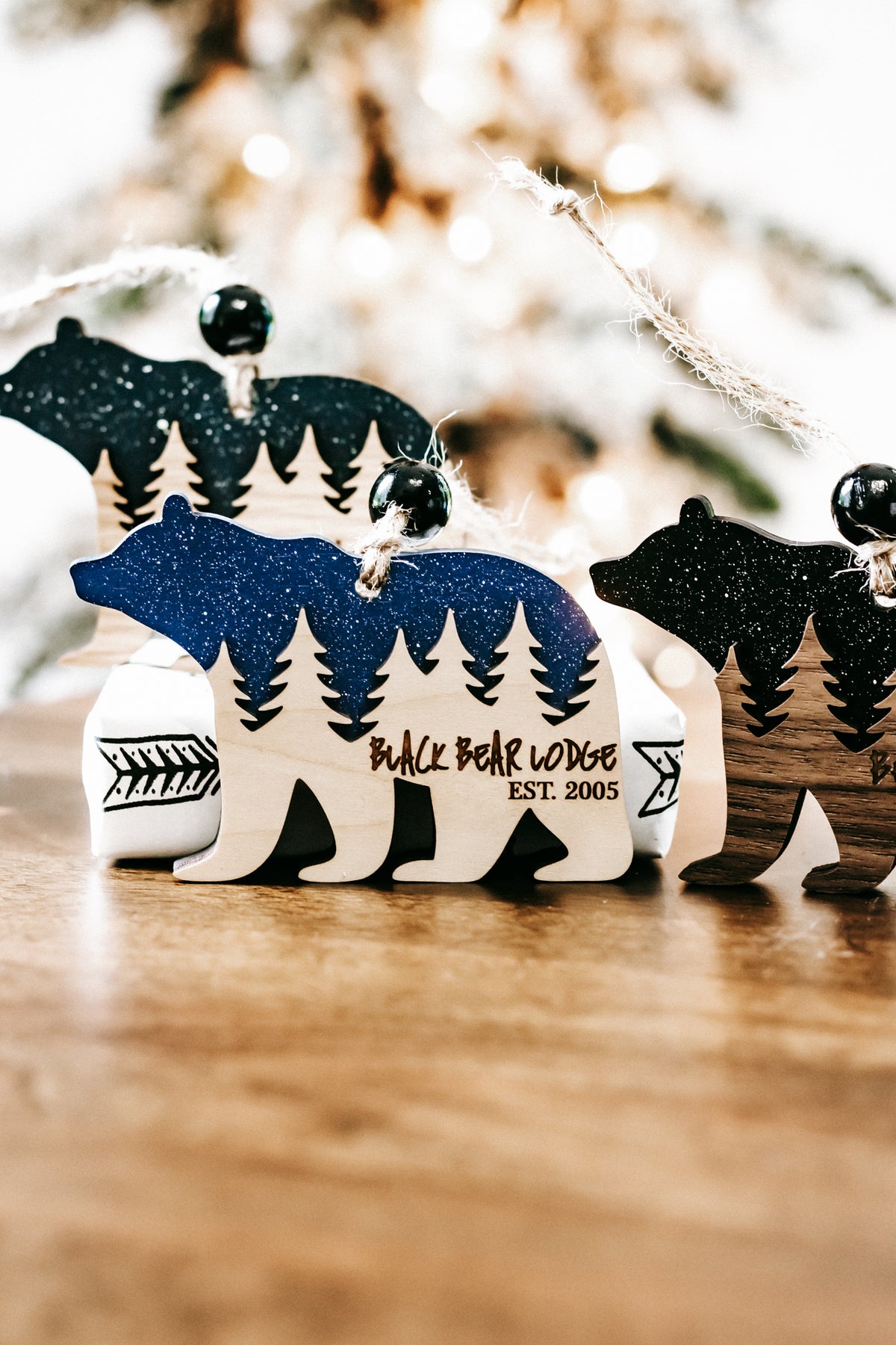 Bear cabin ornament with dark teal glitter bear, pine trees, and cabin graphic details