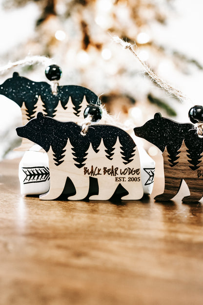 Set of bear cabin ornaments showing dark teal glitter bears and pine tree cabin designs