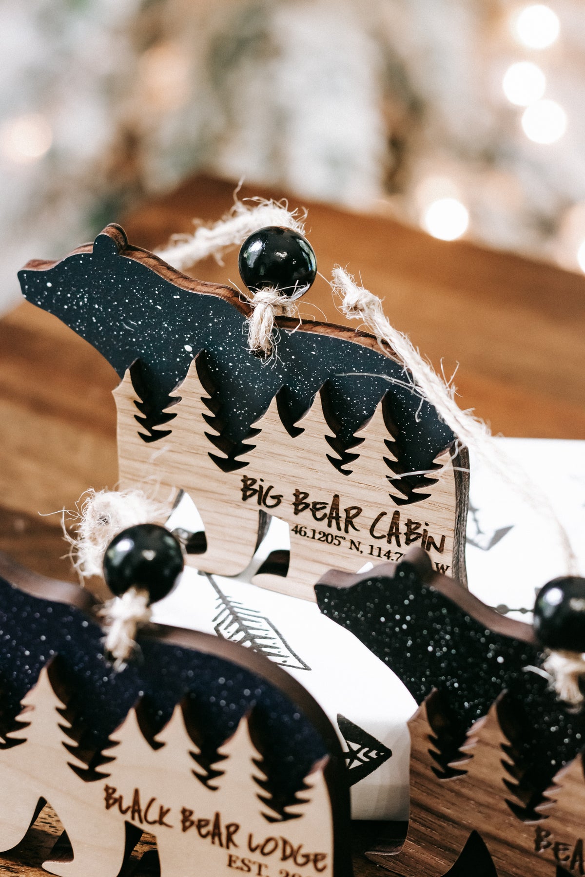Hanging bear cabin ornament with dark teal glitter finish, pine trees, and cabin details