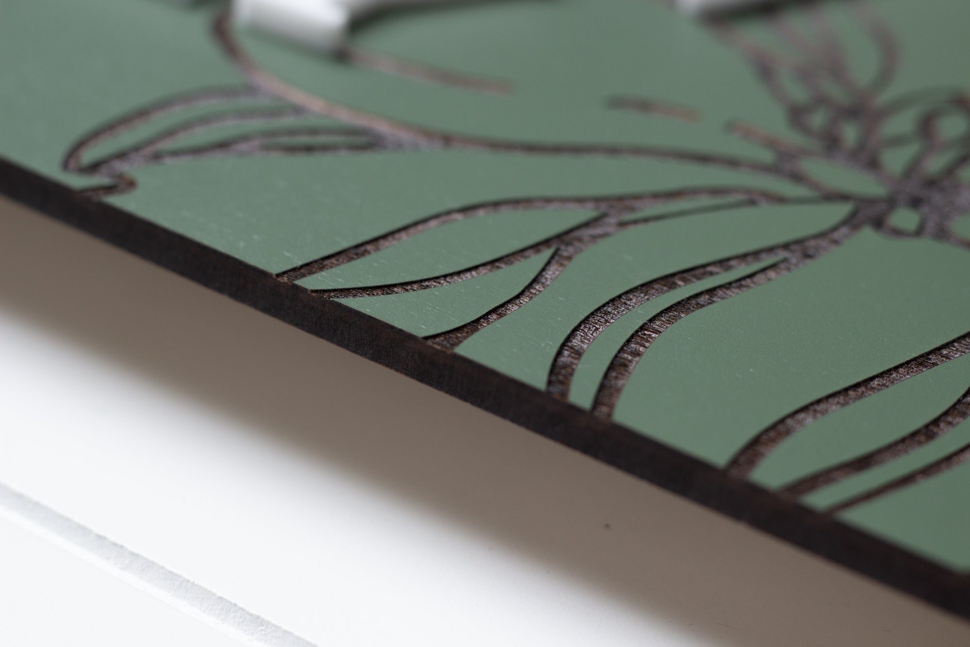 Close-up side view of green rectangle family sign with dark border and floral engraving