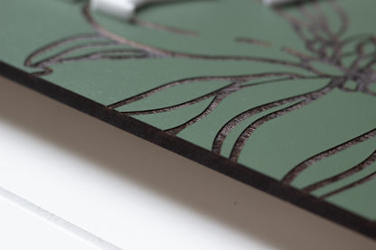 Close-up side view of green rectangle family sign with dark border and floral engraving