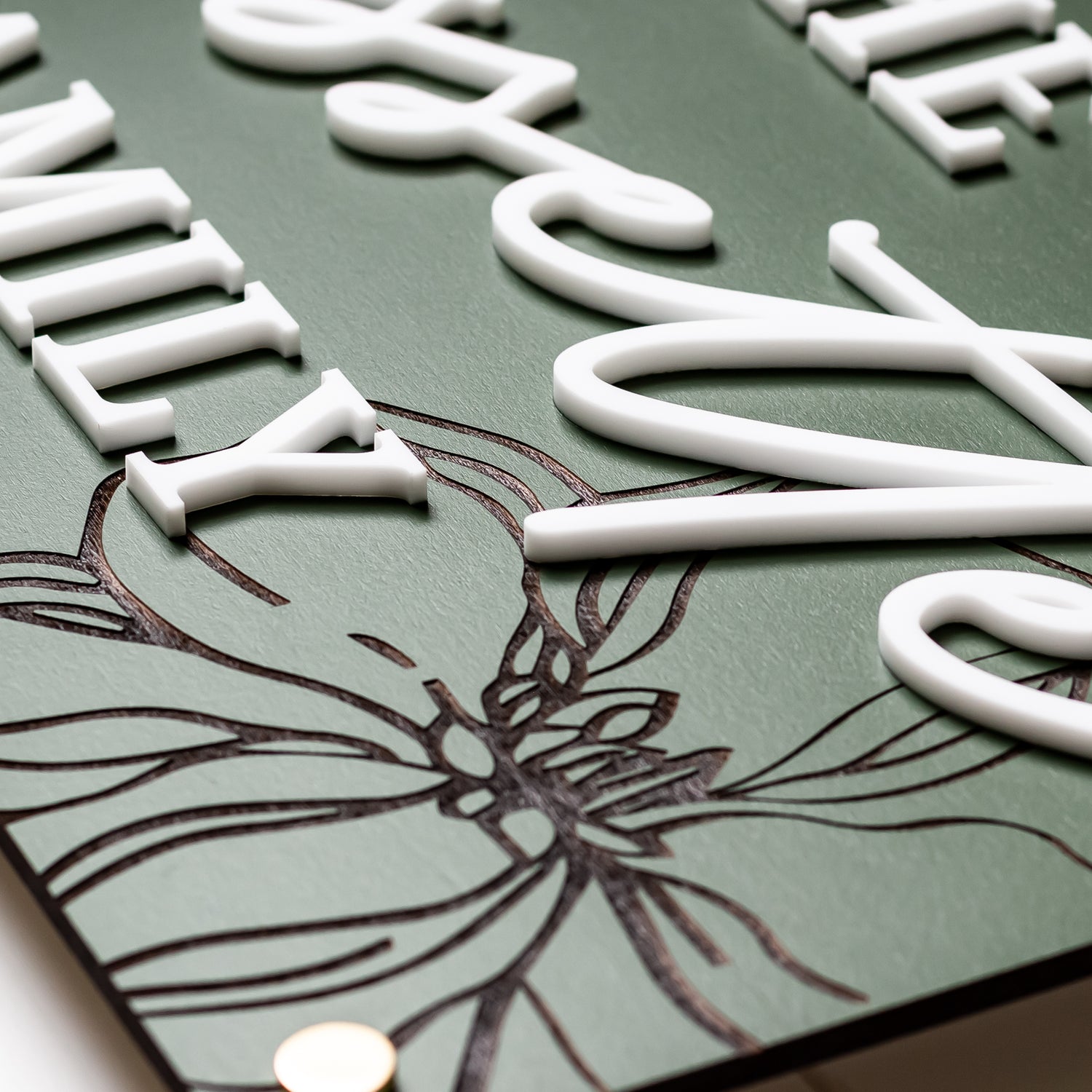 Green rectangle family name sign with white engraved letters and floral line art