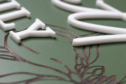 Close-up of green rectangle sign with white letter shapes and floral engraving detail