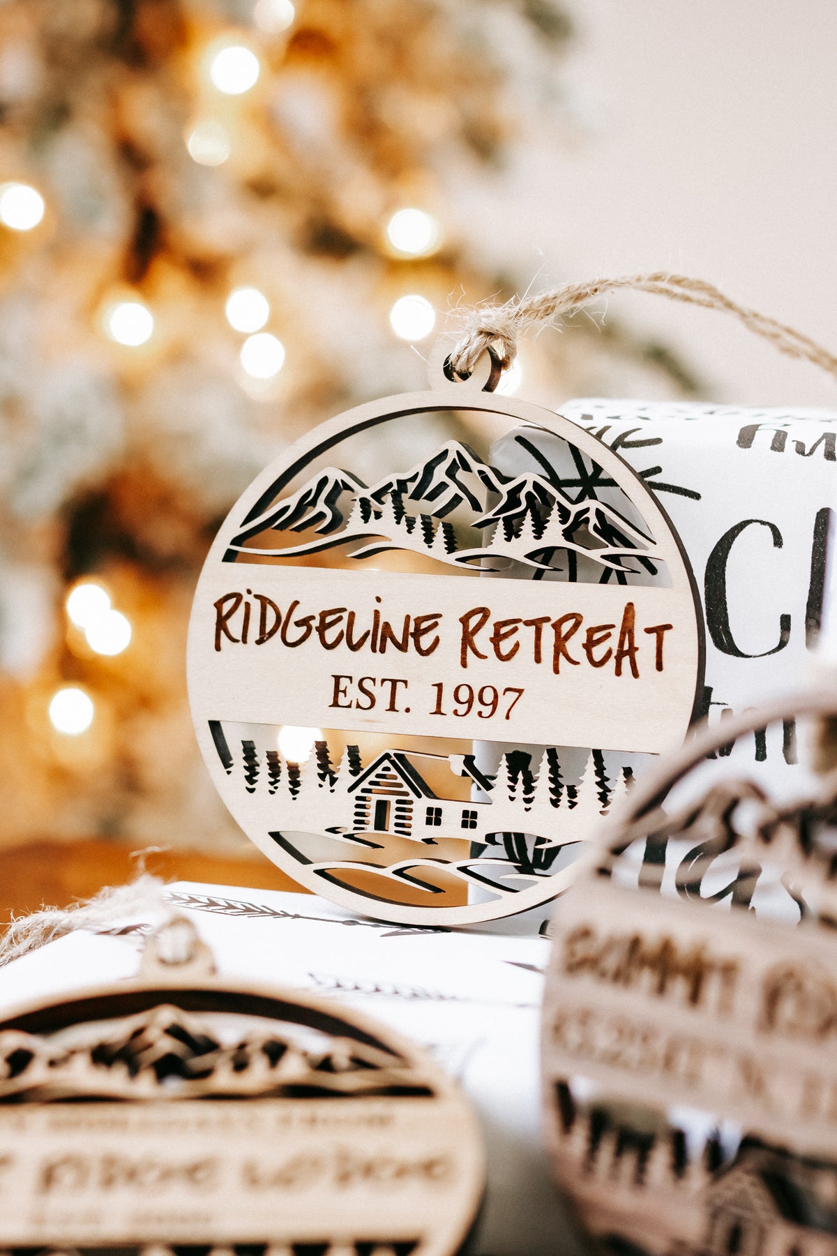 Round engraved wood ornament showing mountain cabin scene and “Riderline Retreat”