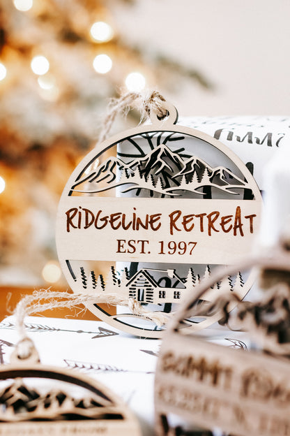 Engraved round wood cabin ornament with “RIDE... RETREAT” and “EST. 1997”, hanging loop