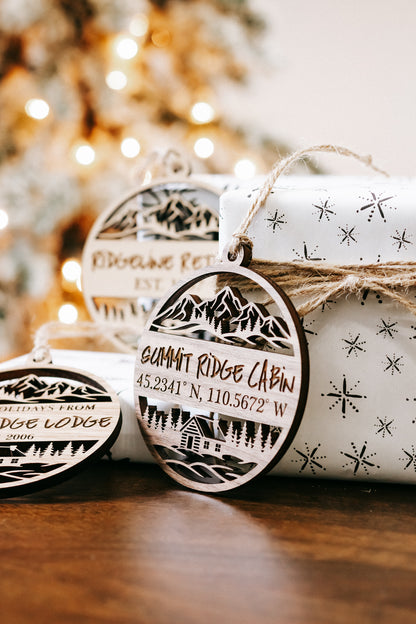 Set of round engraved wood ornaments with cabin scene, coordinates, and star details
