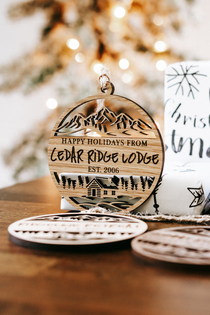 Engraved circular wood holiday cabin ornament reading “Happy Holidays from Cedar Ridge Lodge”