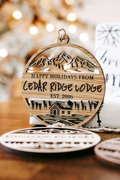 Round engraved wood ornament with “Happy Holidays from Cedar Ridge Lodge” and lodge scene