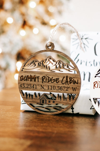Round engraved wood cabin ornament with mountains, coordinates, and “Summit Ridge Cabin”