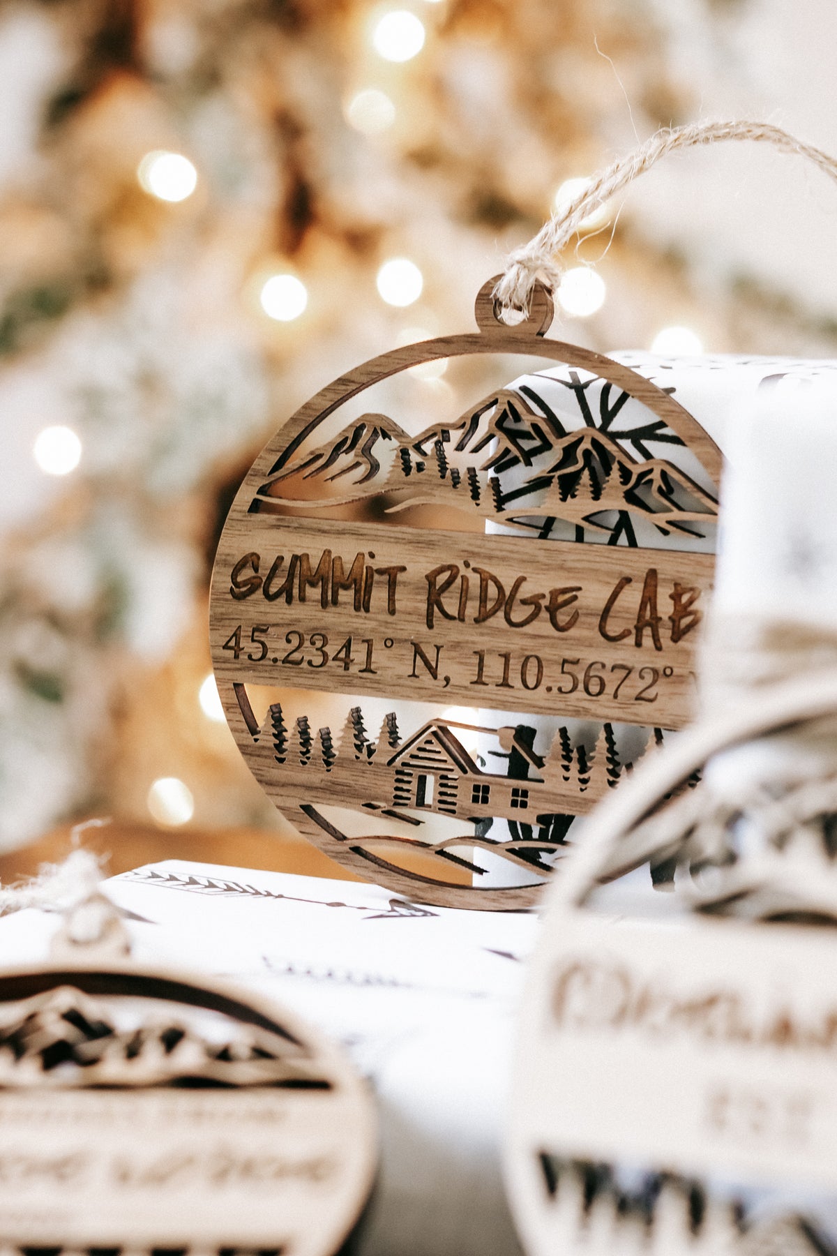 Engraved circular wood cabin ornament reading “SUMMIT RIDGE CABIN” with coordinates, hanging