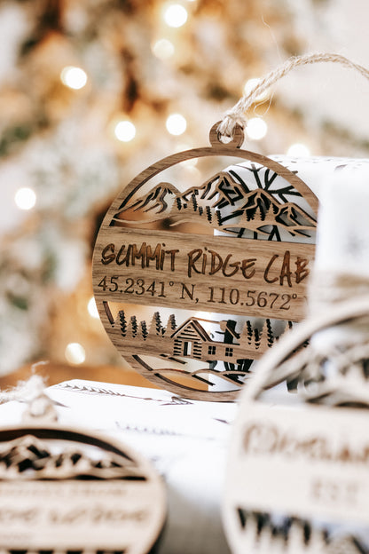 Engraved circular wood cabin ornament reading “SUMMIT RIDGE CABIN” with coordinates, hanging