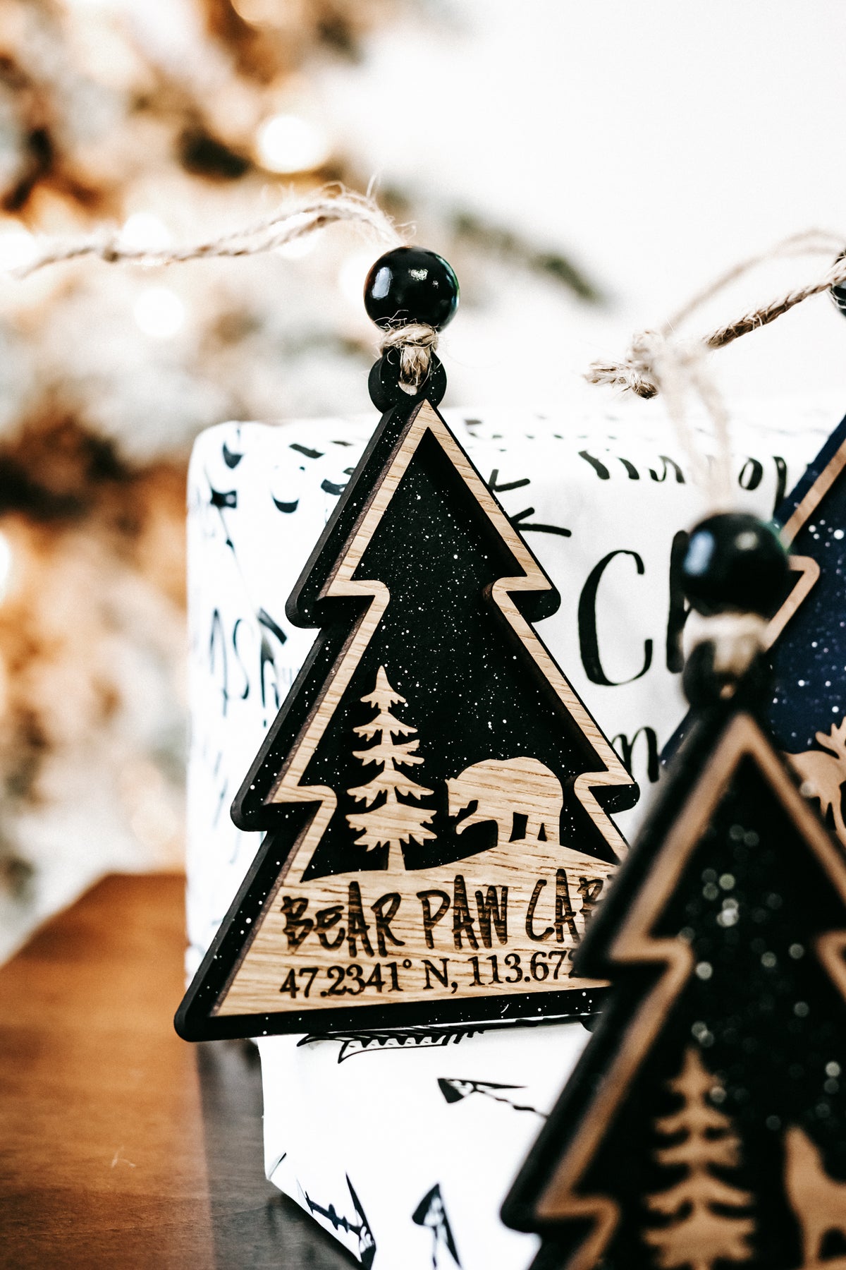 Close-up of dark green tree ornament with gold edge and hanging bead on twine string.
