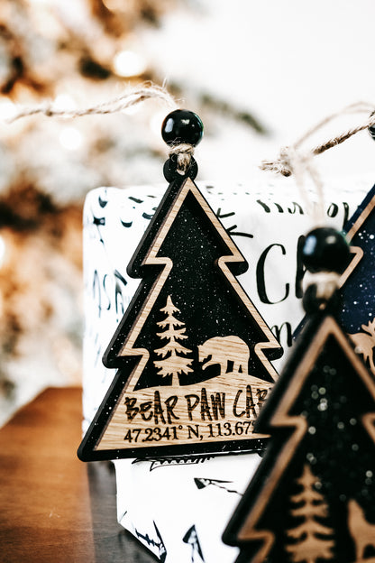 Close-up of dark green tree ornament with gold edge and hanging bead on twine string.