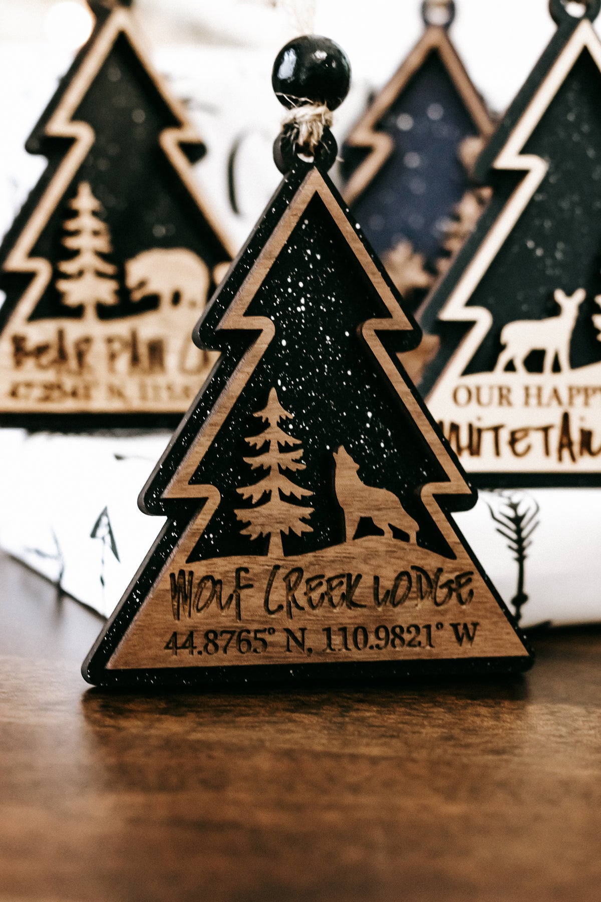 Single wooden tree-shaped ornament with dark green face, gold border, and hanging bead.