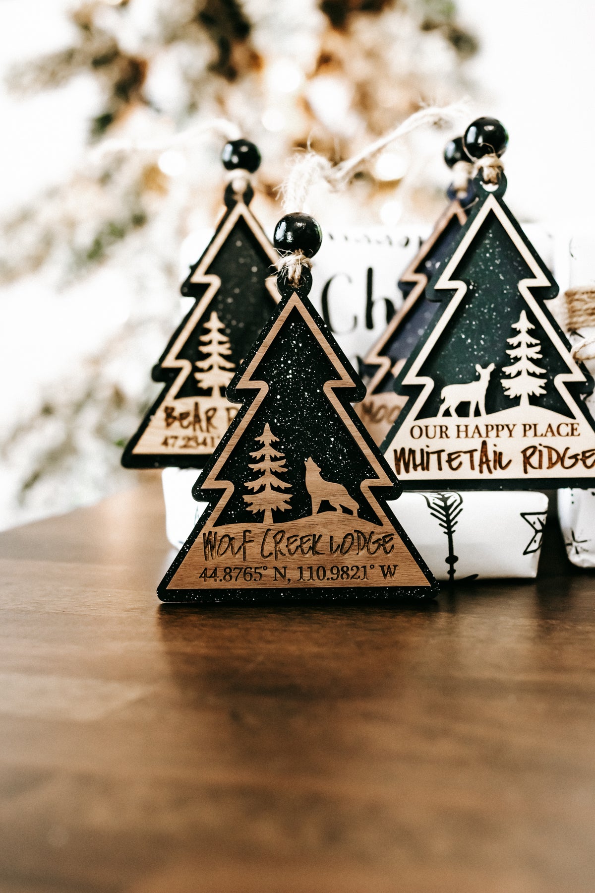 Wooden tree ornaments on display, dark green faces with gold outline and printed text panels.