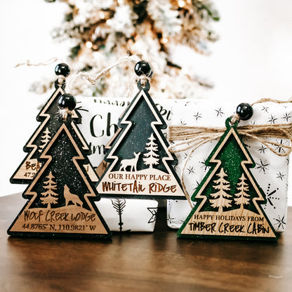 Multiple hanging tree-shaped cabin lodge ornaments with bell-style tops