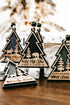 Multiple wooden tree ornaments with hanging beads on twine, dark green centers, gold borders.
