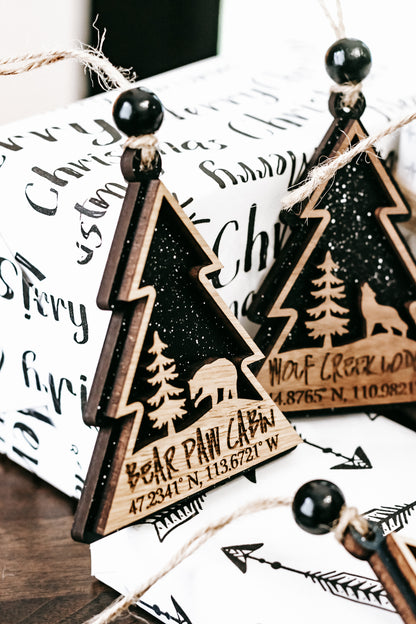 Set of wooden tree-shaped ornaments with hanging beads and printed cabin details on white backs.