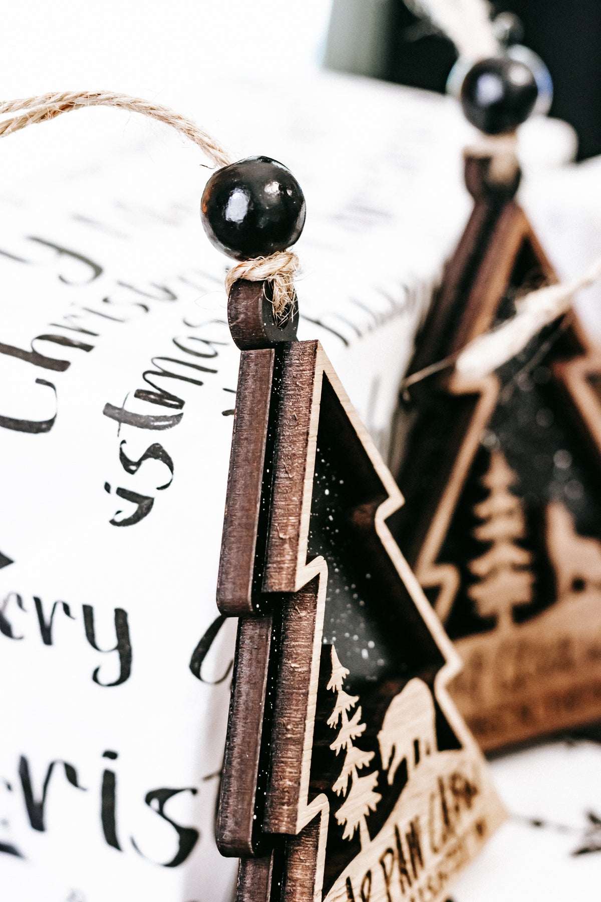 Wooden tree-shaped holiday ornament with dark green center, gold outline, hanging bead.