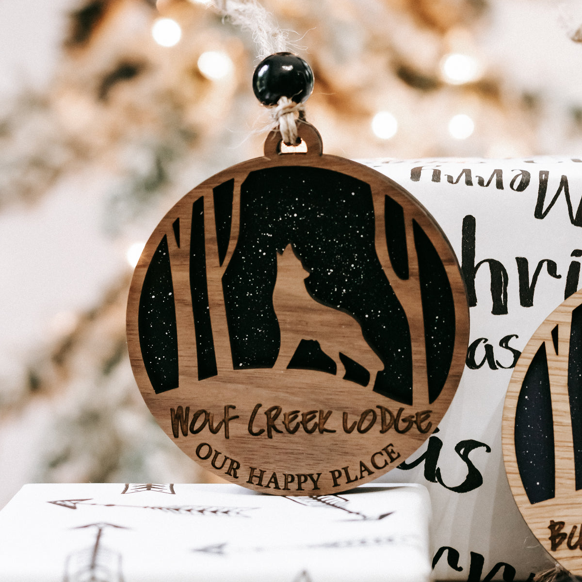 Round wooden Christmas ornament showing deer silhouette with engraved text and hanging hook