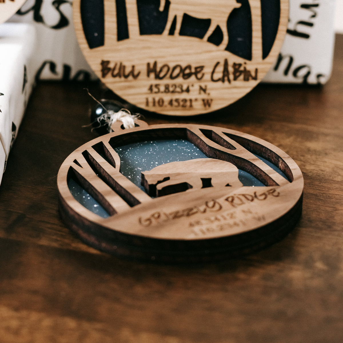 Round wooden Christmas ornament with engraved address text and deer scene on black center
