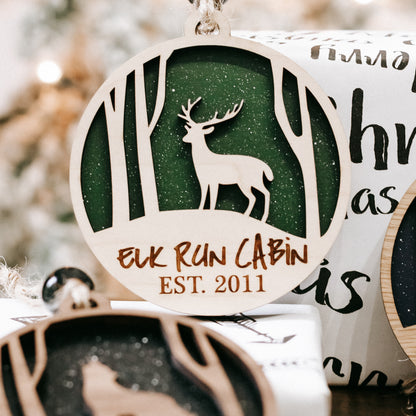 Round wooden Christmas ornament close-up with green deer silhouette and “EST. 2011”