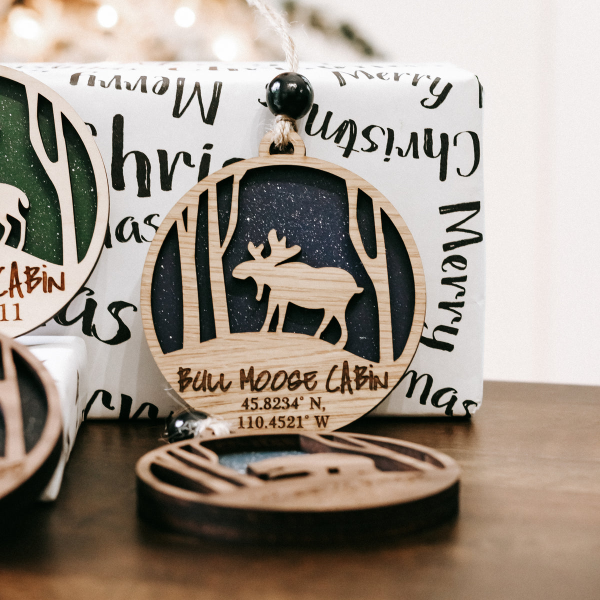 Round wooden Christmas ornament with green deer silhouette and hanging bead hook