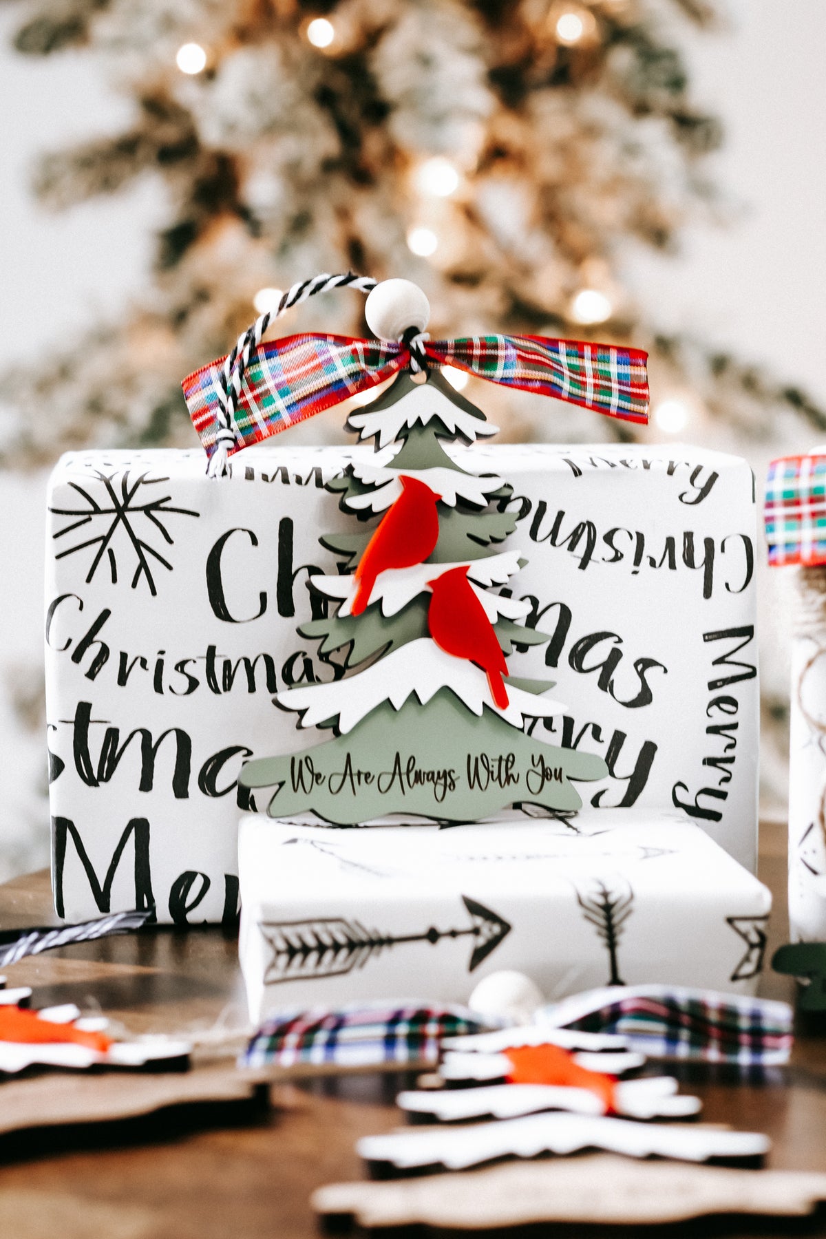 Printed Christmas memorial ornament with red cardinal figures, white trees, and plaid ribbon top
