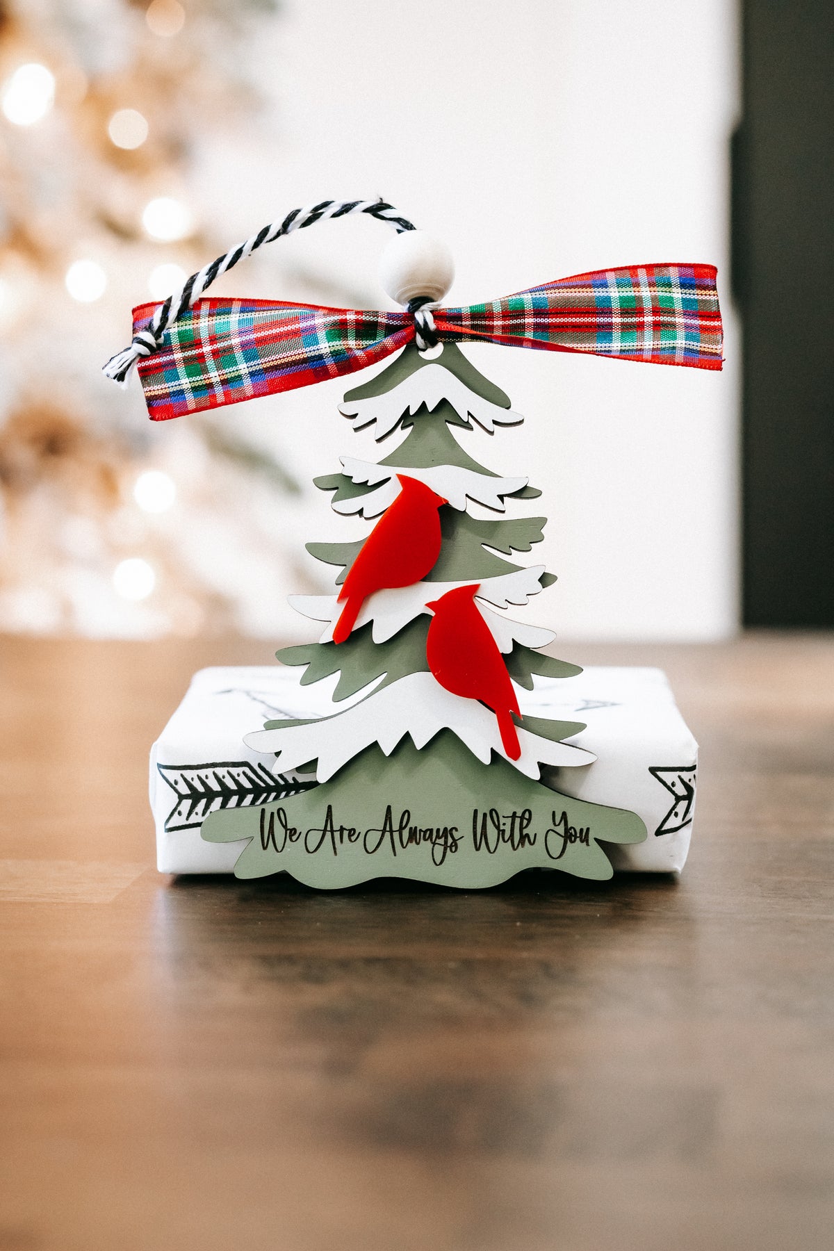 Hanging cardinal ornament on white layered tree base with plaid ribbon bow