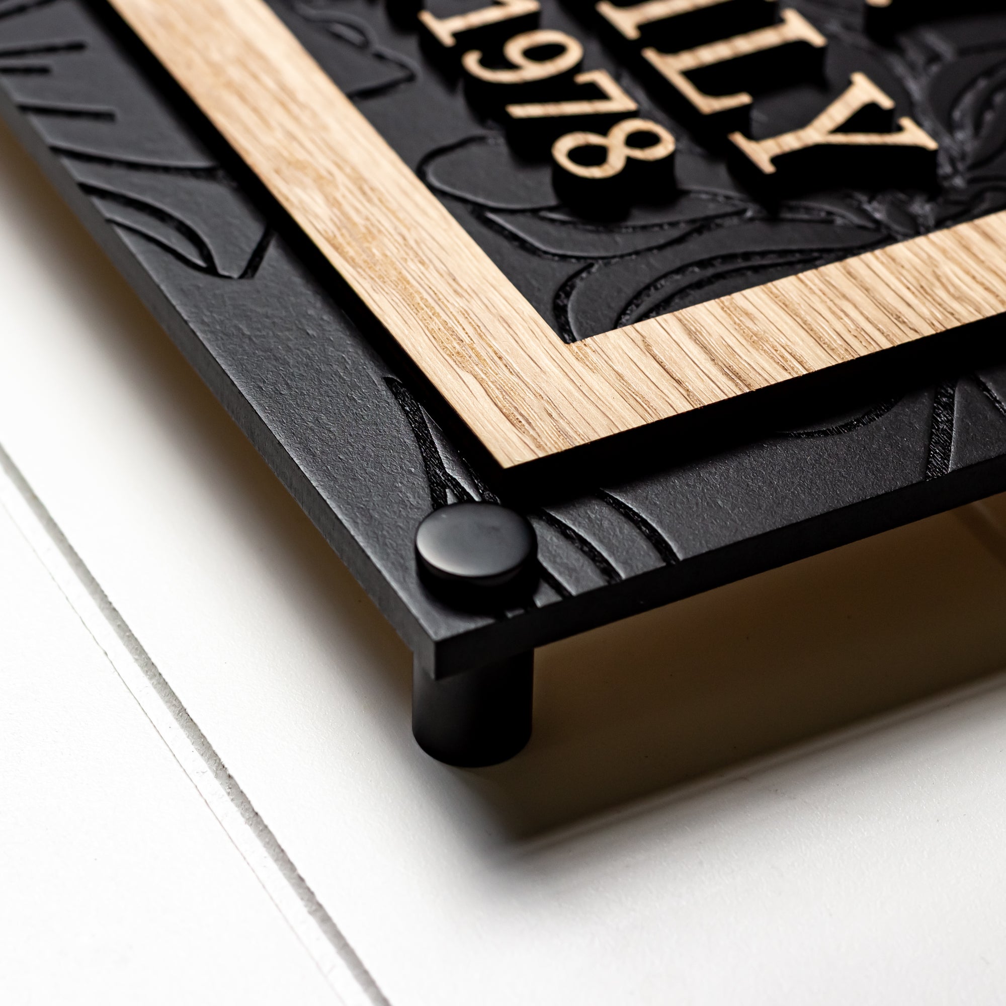 Framed arch family name sign with black backing and light wood border