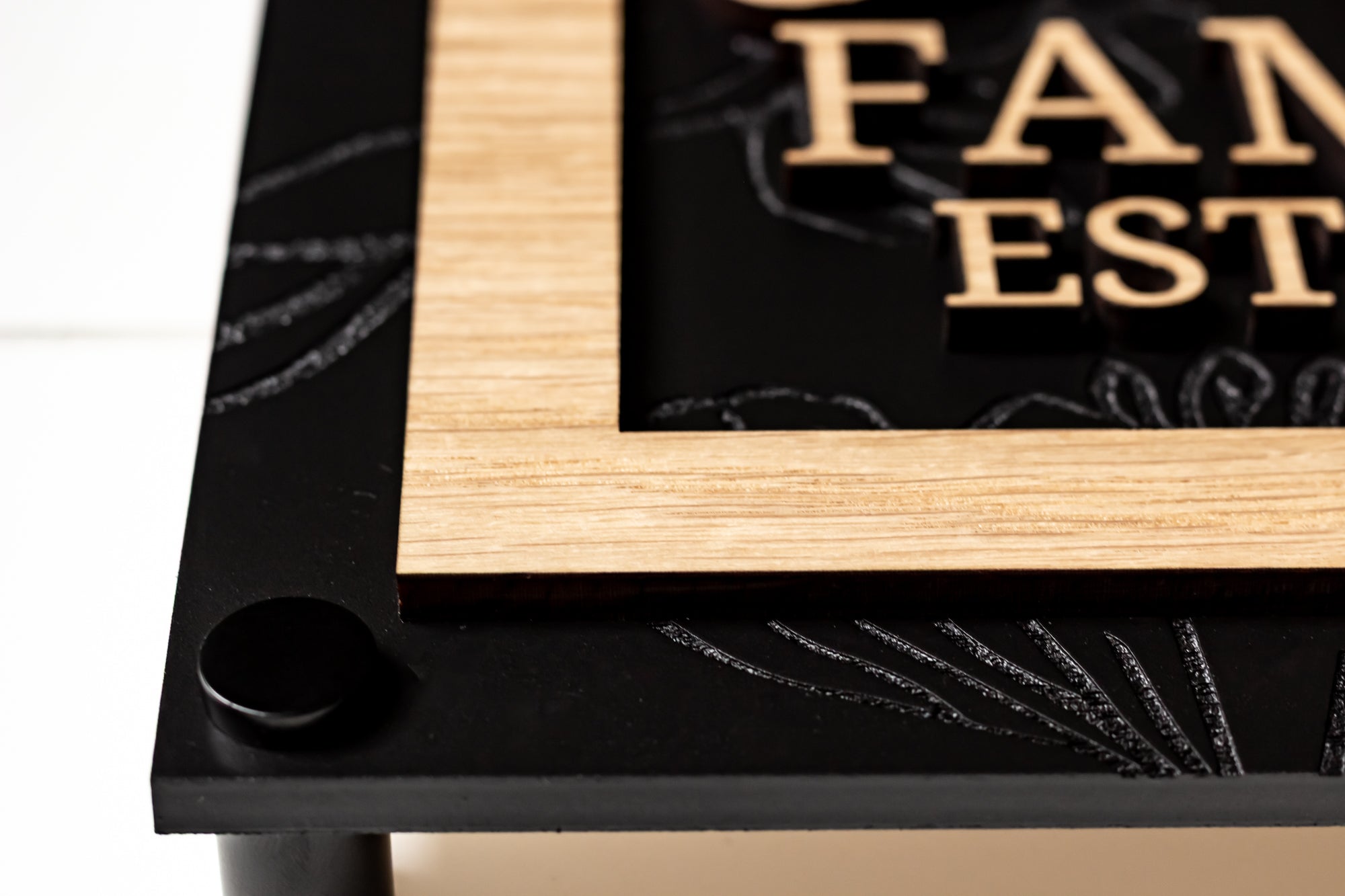 Corner view of framed arch family sign with black base and light wood top