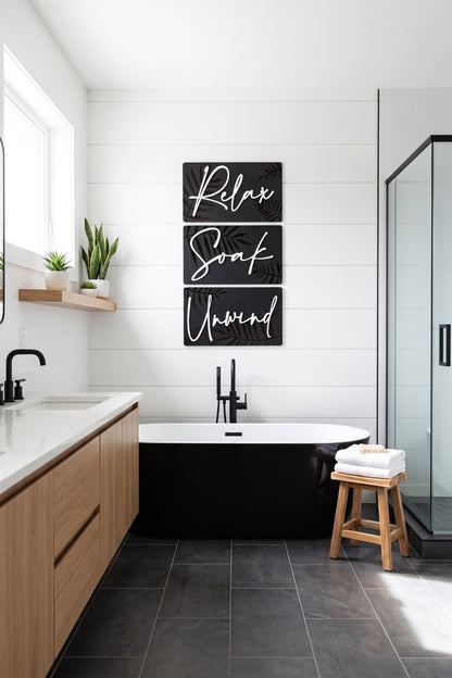 Botanical spa wall art triptych with dark panels, gold leaves, and script “Relax Soak Unwind”