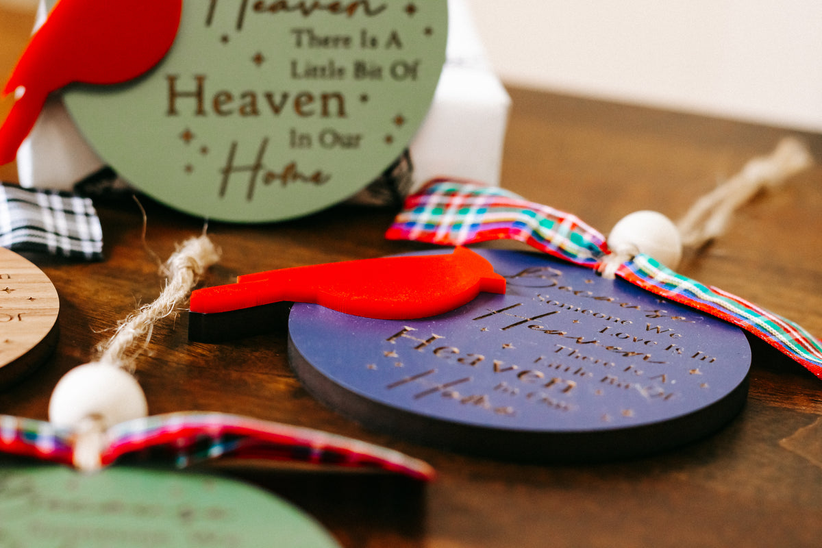 Cardinal memorial ornament close-up with green tag text and red cardinal figure on plaid bow