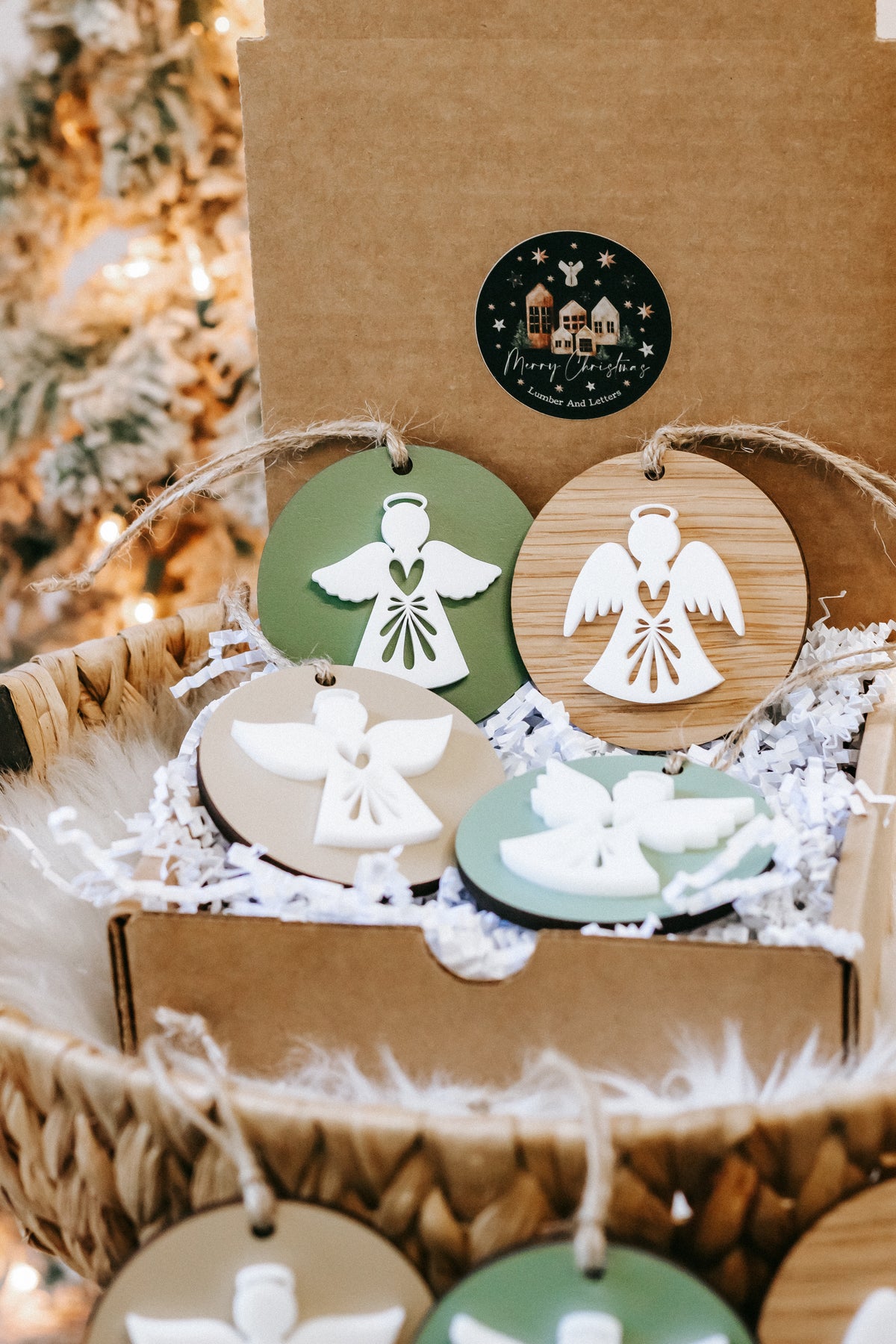Round angel Christmas ornaments with green and wood finishes, hanging on twine in a basket