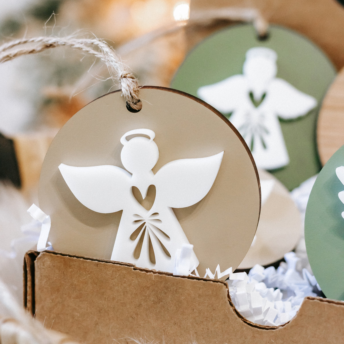 Close-up of round wood angel ornament with white wings and dress, twine hanger loop