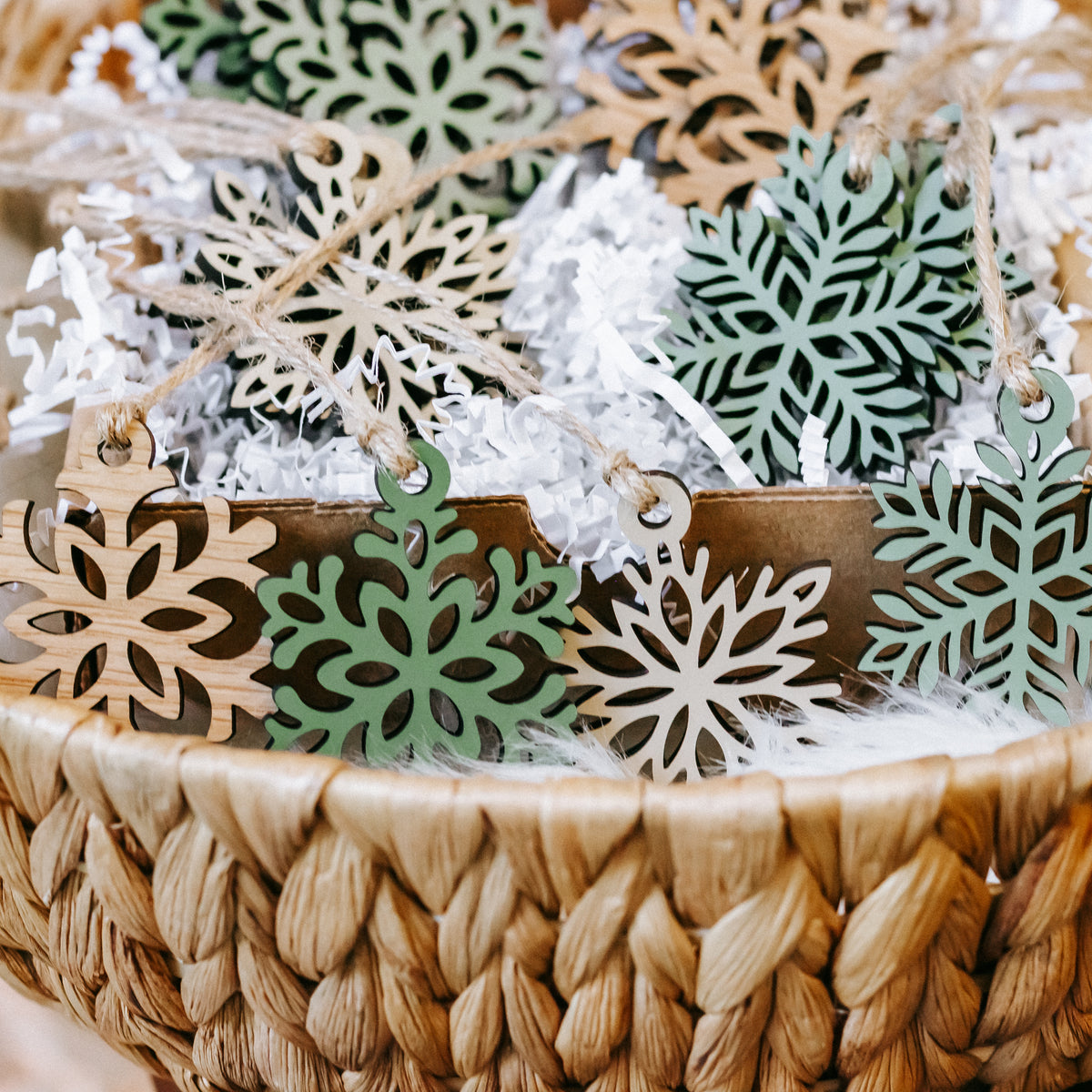Mini wooden snowflake ornaments on twine with green inlays and natural wood edges