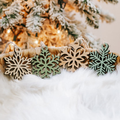 Mini wooden snowflake ornaments with green cutout detailing and twine loops