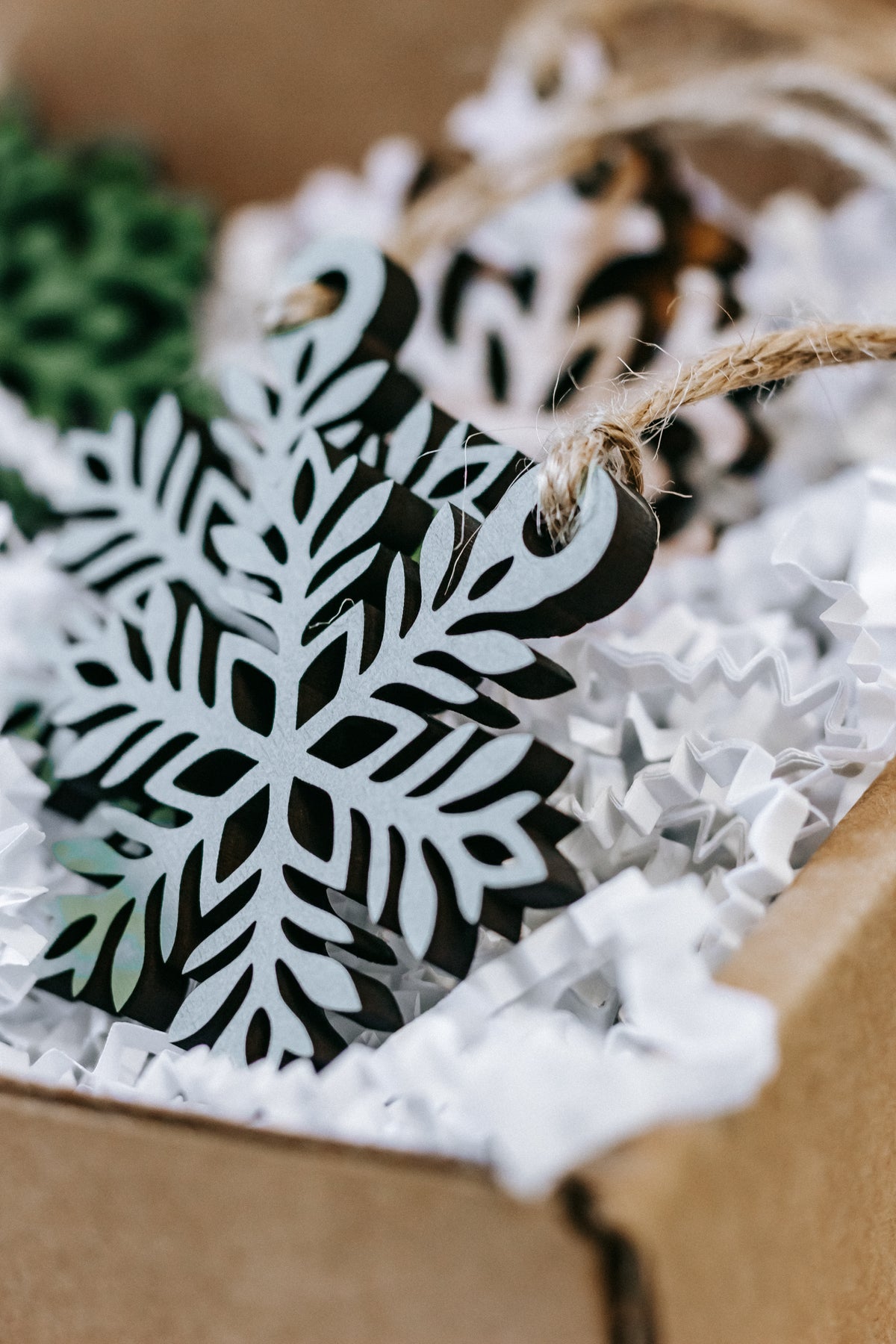 Mini wooden snowflake ornament with green panel and twine loop