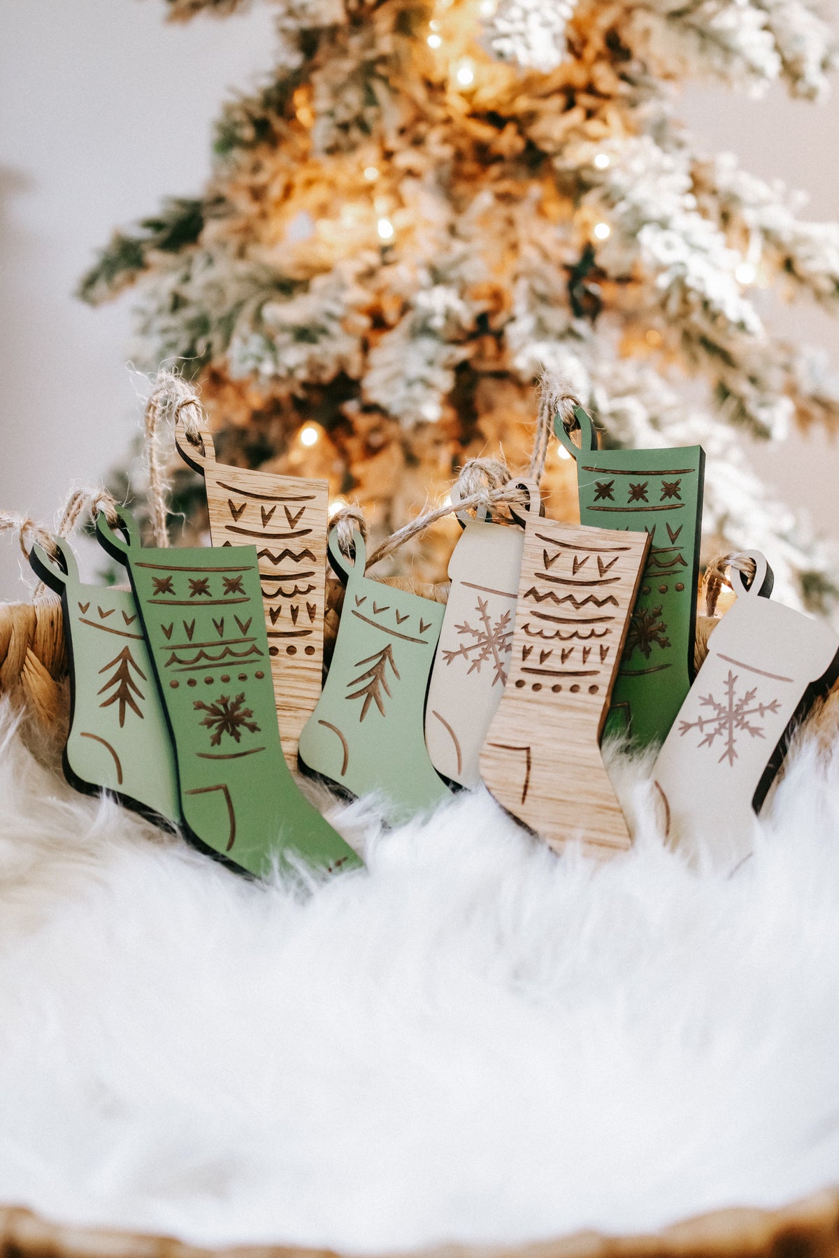 Engraved wooden stocking ornaments with green, cream, and wood designs on a snowy display