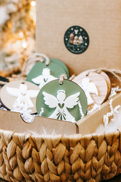 Layered angel ornament with green and white wings on round disc, hanging on twine