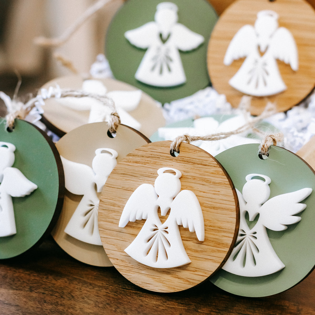 Close-up of round layered angel ornaments, green and wood with white angel cutouts