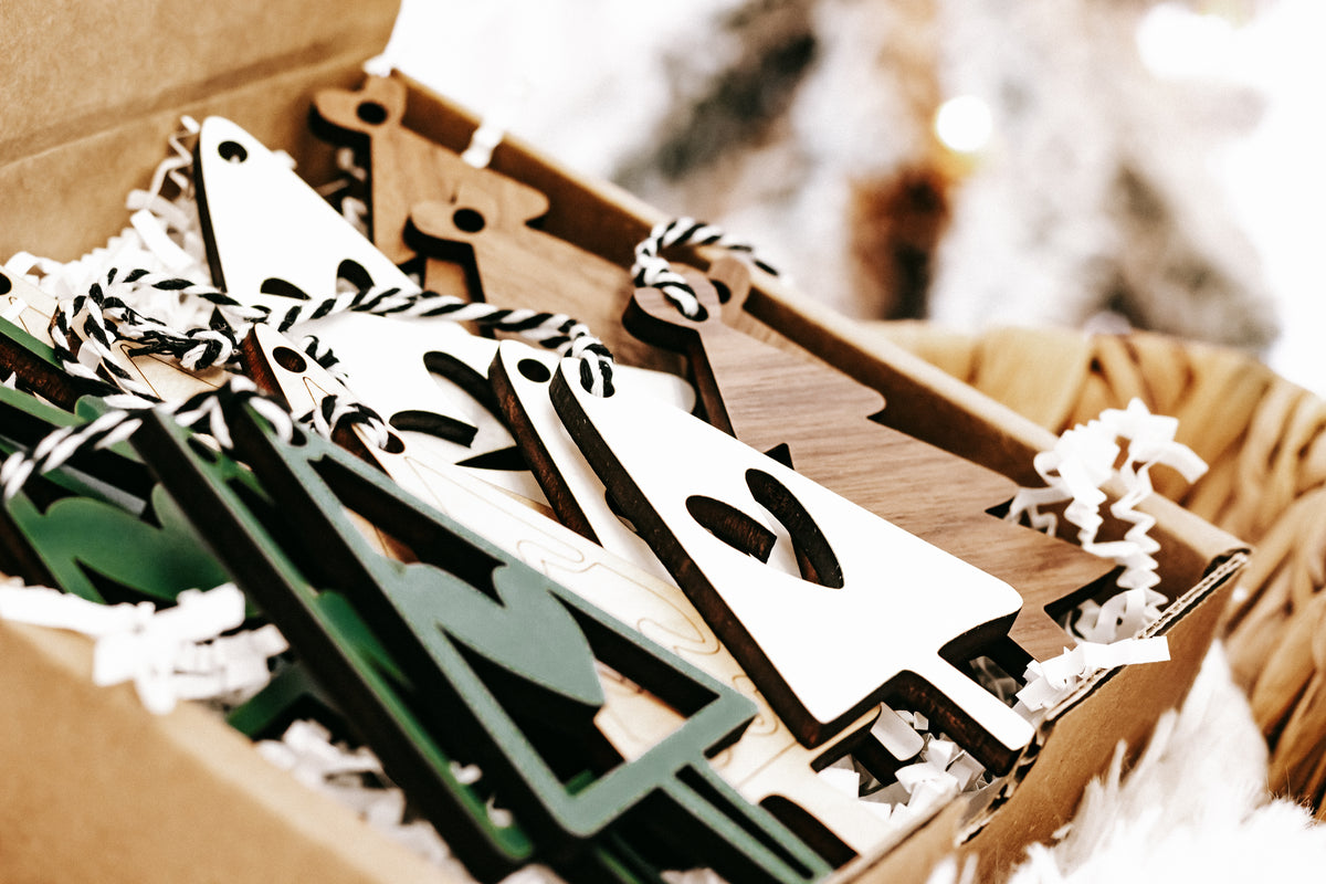 Assorted wooden Christmas ornaments in a box with green tree and white triangle designs